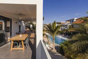 een balkon met een houten tafel en uitzicht op een zwembad bij MaJa appartement Bonaire in Kralendijk