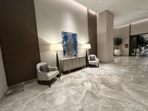 a lobby with two chairs and a painting on the wall at Address Beach Resort Residence in Manama