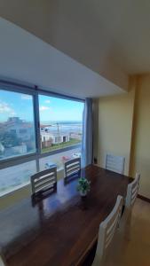 Una mesa de comedor con sillas y una gran ventana. en Apartamento Brisas del Mar, en Santa Clara del Mar