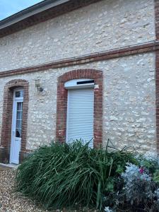 uma porta de garagem num edifício de tijolos com plantas em Gîte Laurymoor - Normandie em Acquigny