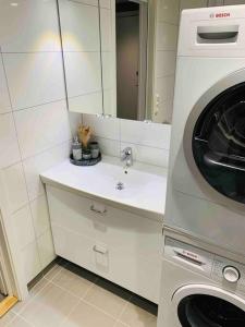 a bathroom with a sink and a washing machine at Lovely and exclusive northern lights apartment with excellent view. in Tromsø