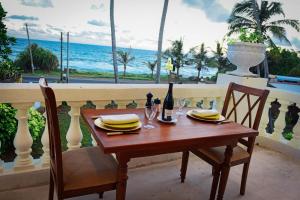 een tafel met stoelen en een fles wijn en uitzicht op de oceaan bij Samsara in Galle