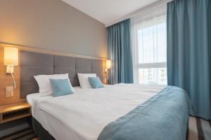 a large bed in a hotel room with a large window at Bel Mare Resort in Międzyzdroje