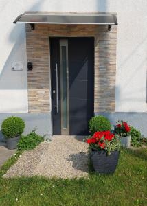 a black door with two pots of flowers in front of a building at Wandorf in Sopron