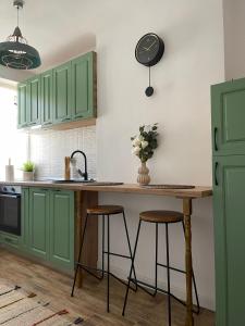 a kitchen with green cabinets and a table with stools at Carol Apartament's in Timişoara +7 photos