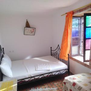Schlafzimmer mit einem Bett und einem Fenster in der Unterkunft Fertassa mtls in Moulay Idris