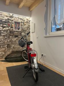 uma bicicleta vermelha estacionada numa sala com uma parede de pedra em La Piccola Casa al Lago - Intera casa con 3 camere e 2 box em Salò