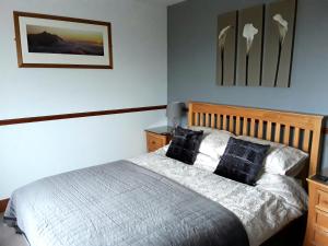 a bedroom with a bed with a wooden headboard at Ruisgarry Bed and Breakfast in Breakish