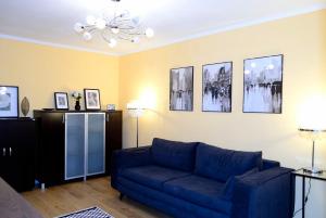 uma sala de estar com um sofá azul e quadros na parede em Cozy 2 Rooms Apartment Drumul Taberei em Bucareste