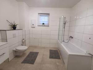 a bathroom with a toilet and a tub and a sink at LOOT: Moderne Wohnung / Zentral in Kitzingen