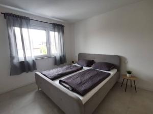 a bedroom with a bed with two pillows and a window at LOOT: Moderne Wohnung / Zentral in Kitzingen