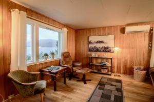 ein Wohnzimmer mit einem Tisch, Stühlen und einem Fenster in der Unterkunft Slåtteng in Svensby
