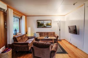 a living room with a couch and chairs and a tv at Slåtteng in Svensby