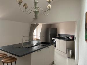 eine Küche mit weißen Schränken und einer schwarzen Arbeitsplatte in der Unterkunft Le Loft in Avallon