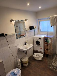 een badkamer met een wastafel en een wasmachine bij Gästezimmer in Springe