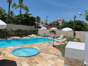 einen Pool mit Stühlen und Sonnenschirmen im Hof in der Unterkunft Studio Mobiliado 52 proximo a praia da Enseada in Guarujá