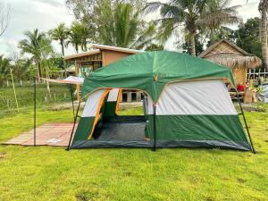 a tent in the grass in front of a house at PJ Kingdom แคมป์ 