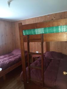 a bedroom with two bunk beds with purple sheets at Cabaña Agradable in Pucón