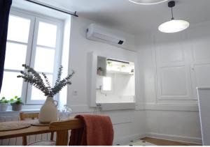 eine weiße Küche mit einem Tisch und einer Vase mit einer Pflanze in der Unterkunft La Maison du Château au calme et centrale in Tournon-sur-Rhône