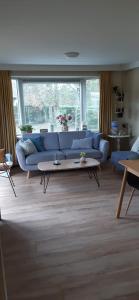 een woonkamer met een blauwe bank en een tafel bij Chalet Wad Mooi in Buren