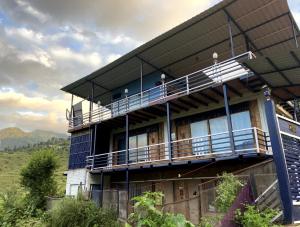 un edificio con un balcón con gente. en Shoonya Home Stay - Devalsari Deodar Forest Range - 60min from Mussoorie, en Mussoorie