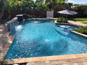 a swimming pool with an umbrella in a yard at Billy's Resort-Clothing Optional- Men Only - Solo Hombres in Wilton Manors