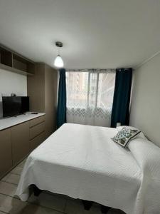 een slaapkamer met een wit bed en een raam bij Acogedor home studio in Santiago