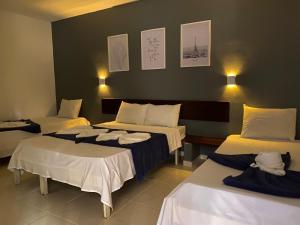 Una habitación con tres camas con toallas. en Pousada Puerta Del Sol Rio das Ostras, en Rio das Ostras 124 fotos más