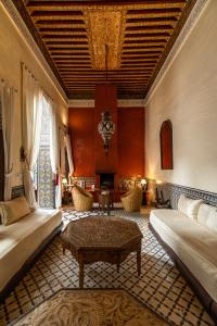 een woonkamer met 2 bedden en een tafel bij Riad Tizwa Fes in Fès