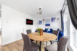 a dining room with a wooden table and chairs at Arte Stays - 3-Bedroom Bright House London, Haggerston, Garden, Parking, 8 min walk to Haggerston Station, weekly or monthly stays, serviced accommodation - 7 guests in London