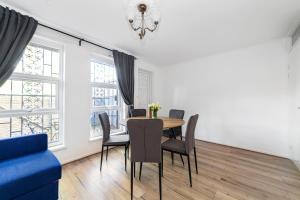 a dining room with a table and chairs and a blue couch at Arte Stays - 3-Bedroom Bright House London, Haggerston, Garden, Parking, 8 min walk to Haggerston Station, weekly or monthly stays, serviced accommodation - 7 guests in London