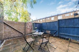 a patio with a table and chairs and a fence at Arte Stays - 3-Bedroom Bright House London, Haggerston, Garden, Parking, 8 min walk to Haggerston Station, weekly or monthly stays, serviced accommodation - 7 guests in London