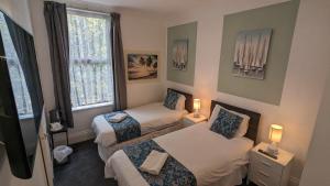 ボーンマスにあるセシル コート ホテルのベッド2台と窓が備わる小さな客室です。