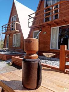 una taza de madera sobre una mesa de madera frente a una casa en Cabañas alpinas alumine en Perito Moreno