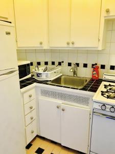 uma cozinha com armários brancos e um lavatório em Stylish Montreal Apartment: Comfortable Stay in the Golden Square Mile em Montreal