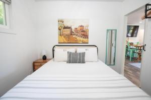 a bedroom with a white bed with a painting on the wall at Snoozy Snail Cottage in Nashville