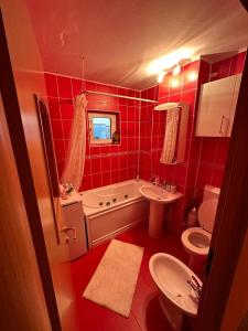 baño rojo con bañera, lavabo y aseo en Orsy House en Făgăraş