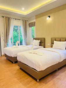 Un dormitorio con tres camas con cisnes. en Koh Yao Modern Inn -SHA Plus en Ko Yao Yai