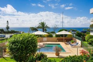 a swimming pool with umbrellas and the ocean at The Headlands Apartments in Alexandra Headland