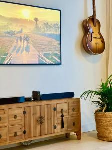 a guitar hanging on a wall next to a dresser at Beachfront Haus Meer in the heart of Arguineguin in Arguineguín