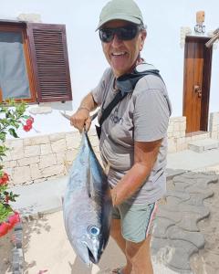 um homem segurando um peixe na mão em Vilas na areia aparthotel em Sal Rei