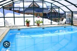 a swimming pool in a greenhouse with snow at Chalet au pied des pistes in Saint-François-Longchamp