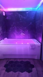 a white bath tub in a room with purple lights at Les nids de la Baie in Favières