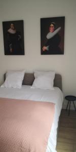 een slaapkamer met een bed met twee foto's aan de muur bij Le voyageur - T2 hyper centre in Abbeville