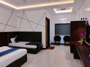 a bedroom with two beds and a desk and chairs at Hotel Om in Betūl