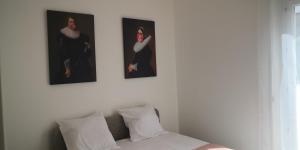 drie schilderijen op een witte muur boven een bed bij Le voyageur - T2 hyper centre in Abbeville