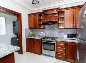 uma cozinha com armários de madeira e um forno com placa de fogão em 1R apartamentos in Santo Domingo em Villa Mella