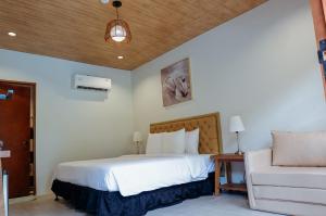 a bedroom with a white bed and a couch at Swissfinity Beach Resort in Pangubatan