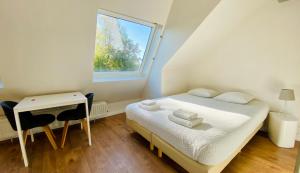 a bedroom with a bed and a desk and a window at Aramis Studio Hotel in Luxembourg