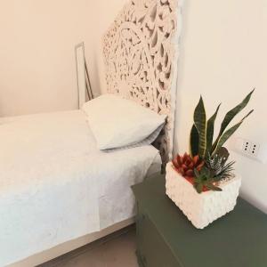 ein Schlafzimmer mit einem Bett und einem Tisch mit einer Topfpflanze in der Unterkunft Palazzo Scianni in Monopoli